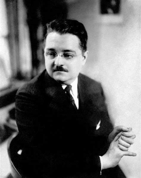 a black and white photo of a man in a suit with his hands folded out