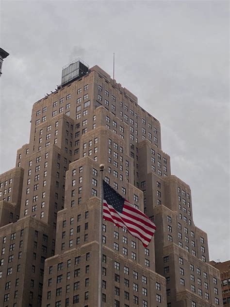 an american flag flying in front of a tall building