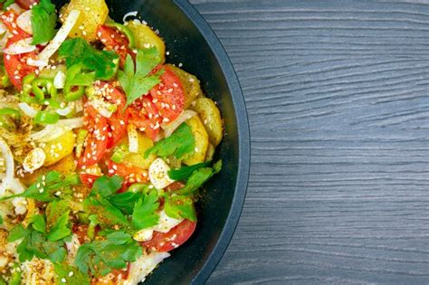 Premium Photo | Cooked fried potatoes with herbs, spices and vegetables in a black pan on a ...