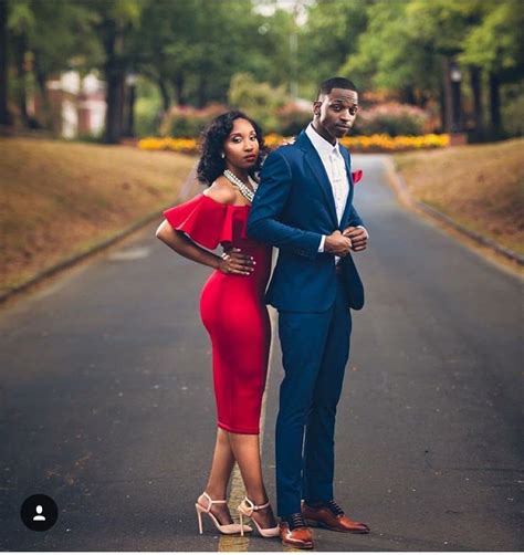 a woman in a red dress standing next to a man in a blue suit