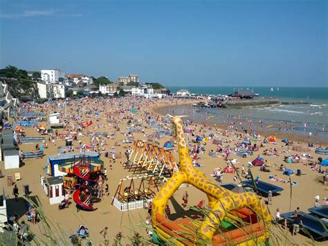 a crowded beach with lots of people on the sand and inflatable water toys