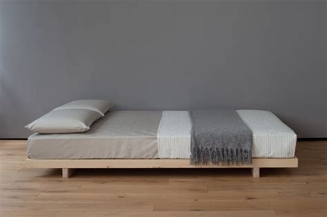 a bed sitting on top of a wooden floor next to a window