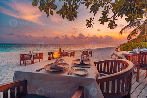 Outdoor restaurant at the beach. Table setting at tropical beach restaurant. Led light candles ...