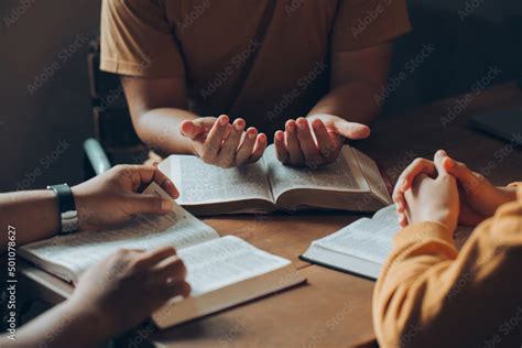 Christians and Bible study concept.Christian family sitting around a wooden table with open ...