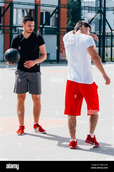 Two strong basketball player playing ball on an urban city basketball court, while wearing black ...