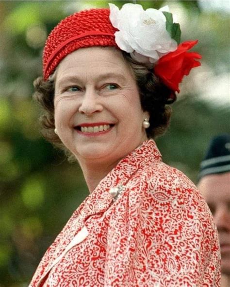 an older woman wearing a red and white flower in her hair smiles at the camera