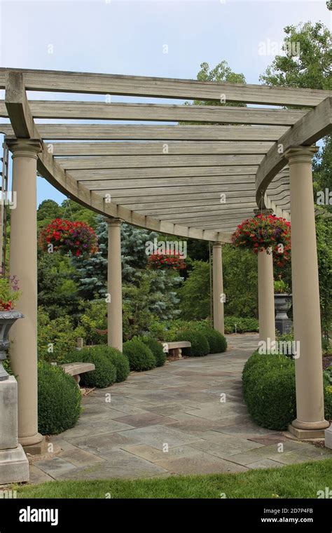 A curved, wood pergola and benches with a stone pathway at the Rotary Botanic Gardens in ...