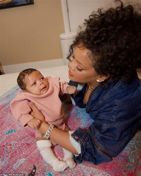 a woman holding a baby on top of a bed next to a pink and blue blanket