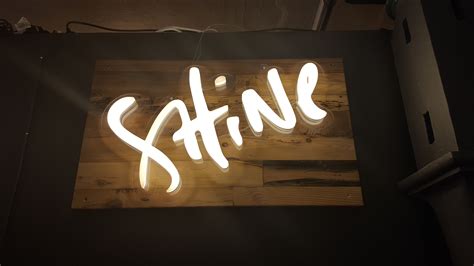 a neon sign that says shine on the side of a wall