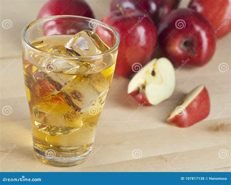 A Glass of Fresh Cold Apple Juice with Ice beside Apples on a Wooden ...