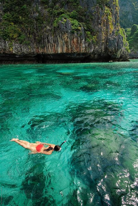 "A Female Tourist Is Snorkeling In Teh Clear Water At Maya Bay With The Cliffs Behind Her." by ...