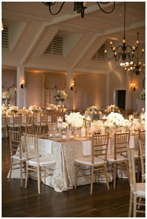 Gold, ivory and white wedding reception decor with white florals in glass vessels, place