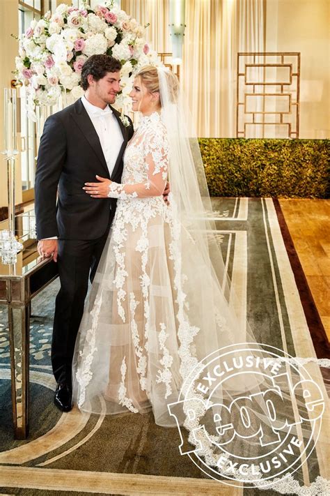 a bride and groom pose for a wedding photo in front of a floral arch at ...