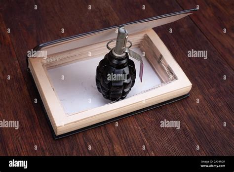 black hand grenade hidden in a book Stock Photo - Alamy