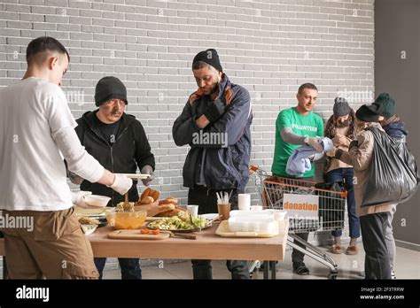 Volunteers giving food and clothes to homeless people in warming center Stock Photo - Alamy