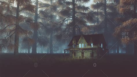 Abandoned house with lights on field in misty autumn forest at night stock photo - OFFSET