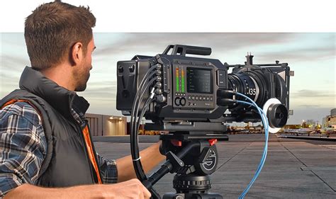 a man holding a camera on top of a tripod in front of an airport