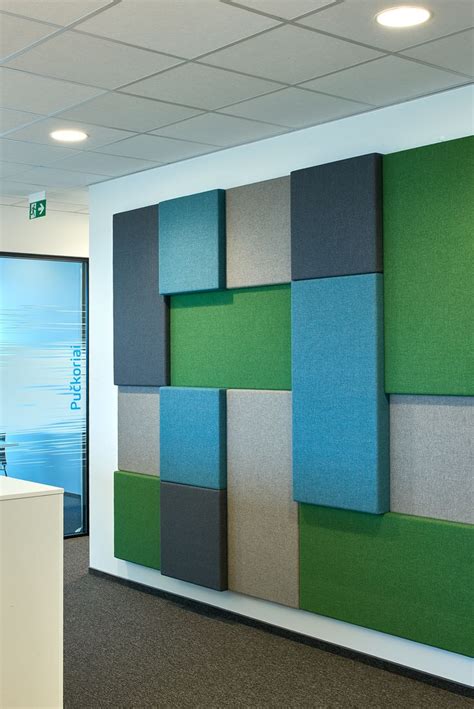 an office cubicle with green, blue and grey squares on the wall next to a white counter