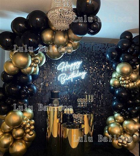 a birthday party with balloons and black and gold decorations on the ...