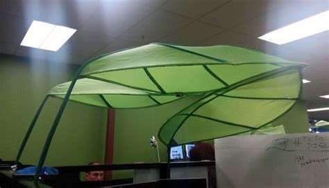 a green umbrella hanging from the ceiling in an office