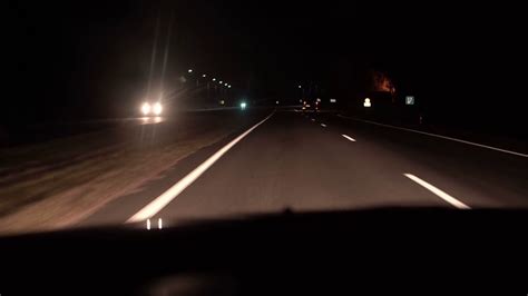 Night road view from inside a car. The headlight and other car in motions on the country road ...