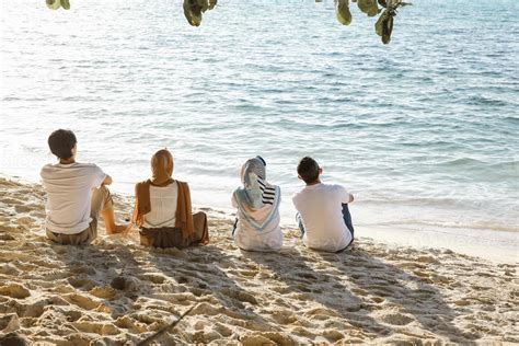 Group of people sitting and relaxing on white sandy beach while enjoying summer holiday at beach ...