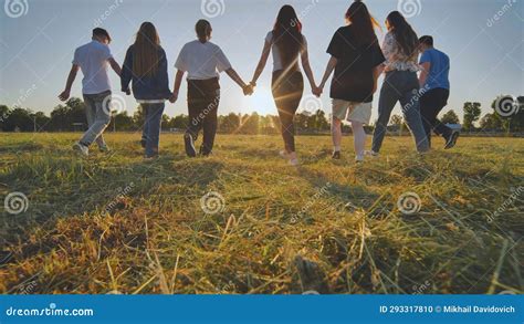 Friends at Sunset Holding Hands Walking Towards the Sun. Stock Photo ...