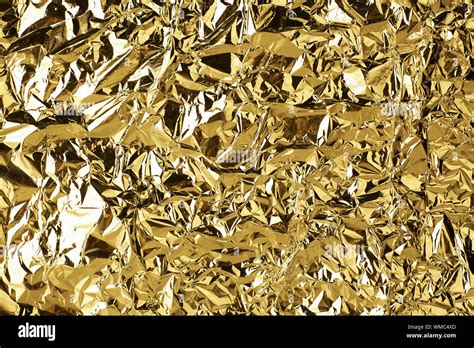 Crumpled golden foil shining texture background, bright shiny gold luxury design, metallic ...