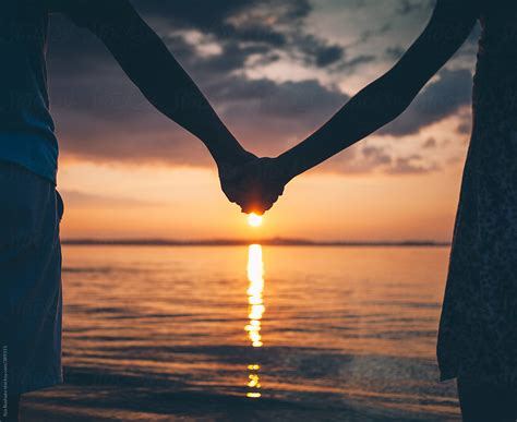 Couple Holding Hands On Nature Beach On Sunset by Ilya - Couple