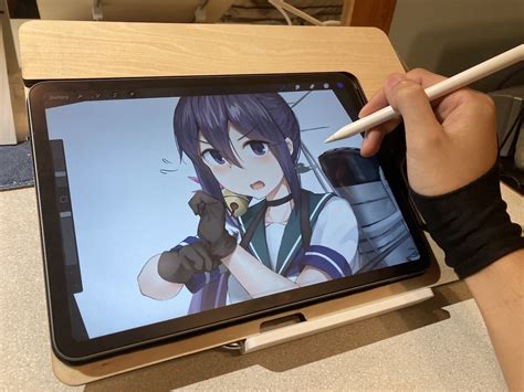 a person holding a pencil and drawing on an ipad with the screen showing anime characters