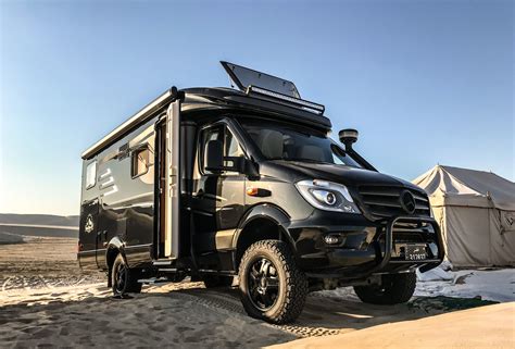 an off - road vehicle parked in the sand with a tent on it's roof