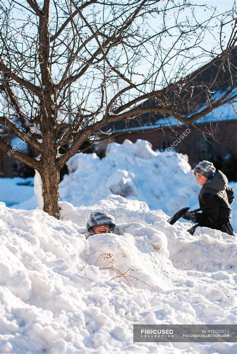 Two boys building snow forts with a shovel on a sunny winter day ...