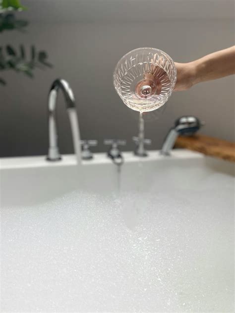 A Person Pouring Champagne into a Bubble Bath · Free Stock Photo