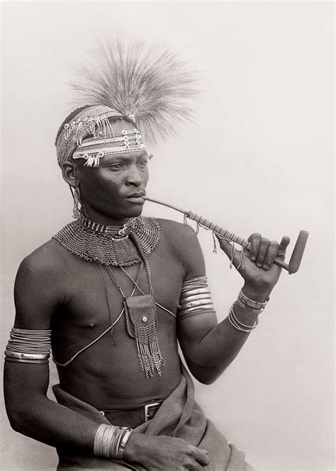 an old photo of a man with feathers on his head and holding a pipe in one hand