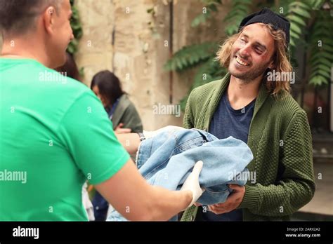 Volunteers giving clothes to homeless people outdoors Stock Photo - Alamy