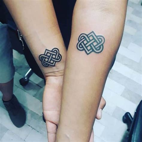 two people holding hands with tattoos on their arms and wristbands, both have intertwined