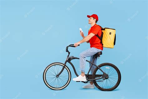 Premium Photo | Male Courier With Backpack Using Cellphone Riding Bike Blue Background