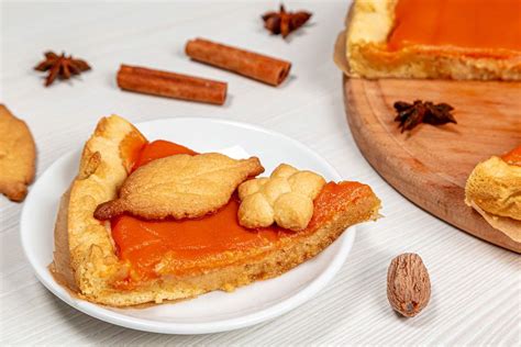 Homemade pumpkin pie with red autumn leaves on white wooden table. Top ...