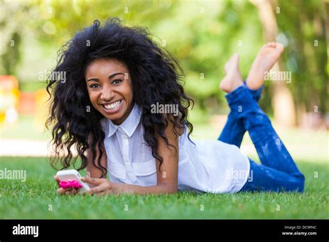 Smiling teenage black girl using a phone, lying down on the grass - African people Stock Photo ...