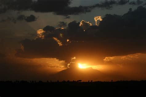 the sun is setting behind some clouds in the sky