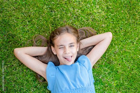 Joyful teen girl lying on grass, top down view Stock Photo | Adobe Stock