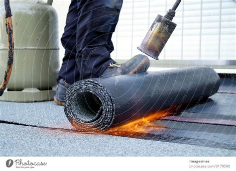 Flat roof installation with roofing felt, propane gas burner gas bottle. Construction work with ...