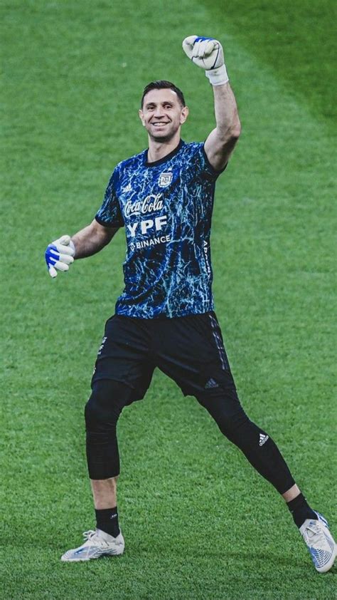 a man standing on top of a lush green field holding a soccer ball and glove