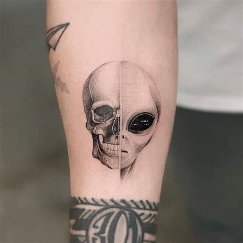 Micro-realistic skull and alien head tattoo on the