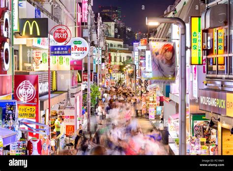 Crowds walk through Takeshita Street in the Harajuku district at night ...