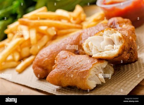 A delicious crispy battered deep fried fish and chips with greens and ketchup Stock Photo - Alamy