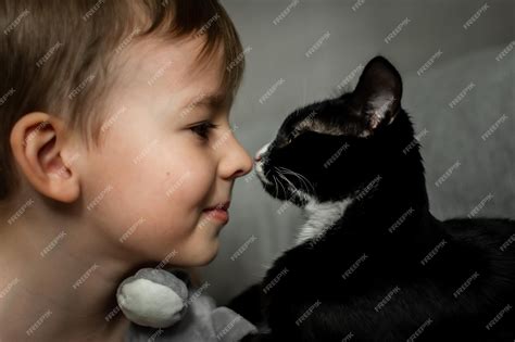 Premium Photo | A young boy is kissing a black and white cat.