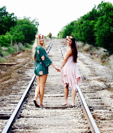 two women standing on train tracks holding hands