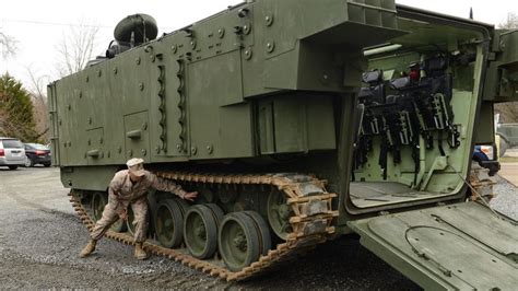 a man is standing next to an army tank