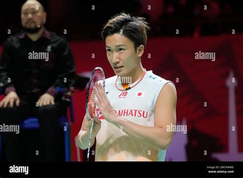 Japan's Kento Momota gestures as he retires due to injury during his men's singles group stage ...